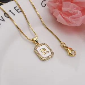 Detailed view of a square gold pendant necklace featuring the letter R with shell inlay