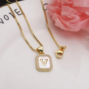 Detail of gold-plated square pendant necklace with shell inlay and letter V.