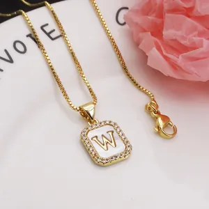 Close-up of gold square pendant featuring letter W on white shell with zircon border