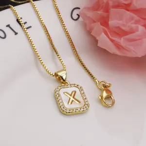 Detailed macro view of gold-plated square letter X pendant with shimmering shell base
