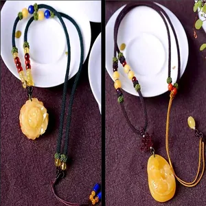 Detailed view of hand-woven necklaces with yellow amber-style flower and oval pendants