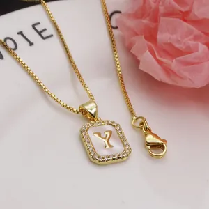 Macro view of gold letter Y necklace pendant featuring zircon halo and shell inlay detail