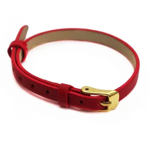 Vue détaillée d'un bracelet fin en cuir rouge avec une boucle en or polie.
