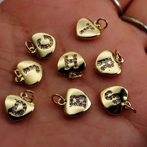 Macro detail of gold-plated heart charms with micro-inlaid zircon letters for DIY jewelry
