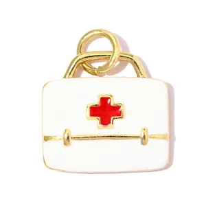 Détail macro d'un pendentif boîte médicale en émail blanc et rouge avec bordure dorée DIY.