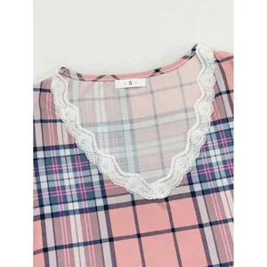 Dettaglio della parte superiore del pigiama rosa a quadri da donna con scollo a V e pizzo bianco
