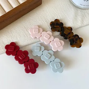 Nahaufnahme von vier bunten Blumen-Haarspangen in Rot, Rosa, Blau und Schildpatt-Optik.