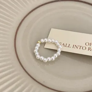 Vista dettagliata di un elegante anello di perle minimalista con una perla dorata