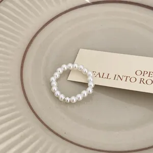 Dettaglio di un elegante anello di perle su un piatto di ceramica con cartolina.