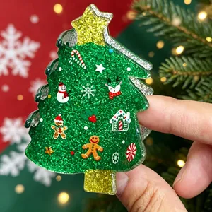 Close-up of a green glitter Christmas tree hair claw clip featuring small festive motifs