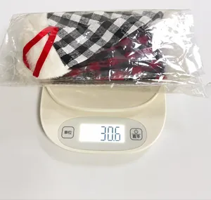 Detail shot showing three Christmas plaid cutlery holders with plush trim on a digital scale