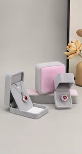 Detailed view of grey and pink velvet jewelry boxes featuring a red gemstone necklace and ring