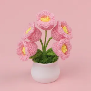Simpatica pianta in vaso con fiori rosa fatti all'uncinetto su sfondo rosa tenue.