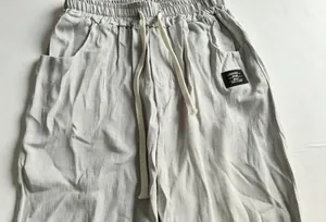 Gros plan détaillé d'un pantalon en lin et coton gris clair avec cordon et écusson
