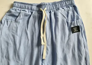 Détail d'un pantalon en coton et lin bleu clair avec taille élastique et cordon