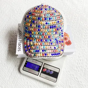 Dettaglio del peso del cappello da baseball colorato con perle e strass su bilancia