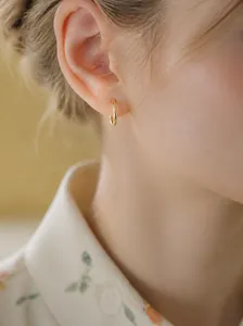 Nahaufnahme eines minimalistischen goldenen Creolen-Ohrrings mit eleganter Textur