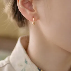 Eleganter minimalistischer kleiner Creolen-Ohrring aus 18k Gold an einem asiatischen Model