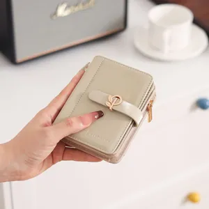 Detailed macro view of a beige PU leather women's short wallet with a leaf buckle.