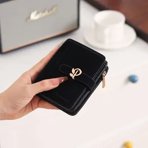 Detailed close-up of a black PU leather short wallet with an elegant golden leaf clasp