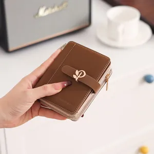 Close-up detail of a brown PU leather women's short wallet featuring an elegant gold leaf buckle