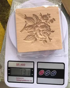 Blumige Keksform aus Holz auf einer Küchenwaage, Gewicht 131 Gramm