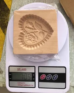 Detailansicht einer hölzernen Herz-Rose-Keksform, die 109 Gramm auf einer Küchenwaage wiegt