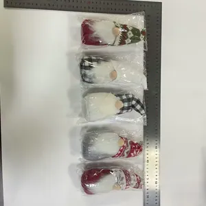Macro view of five assorted Christmas gnomes in plastic packaging next to a metric ruler