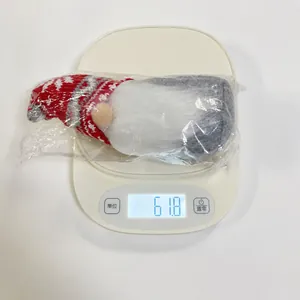 Christmas gnome doll with snowflake hat being weighed at 61.8g on scale