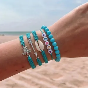 Close-up of bohemian hand-woven turquoise bracelet set with shell and turtle charms