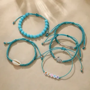 Detailed view of 5 turquoise bohemian hand-woven bracelets with shell and turtle charms.