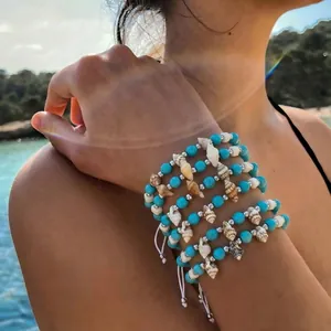 Close-up view of a Bohemian stackable shell bracelet set with vibrant turquoise beads.