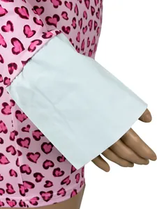 Dettaglio di una tuta rosa con stampa a cuori e ampio polsino bianco a contrasto
