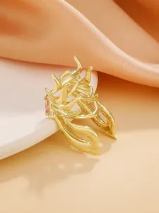 Close-up detail of creative gold beetle ring with organic curves and pink gemstone accent.