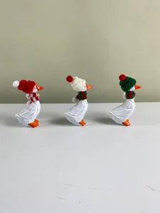 Vue détaillée de trois figurines d'oies blanches portant des bonnets et écharpes de Noël