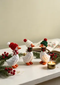 Trois figurines de canards de Noël en bois portant des bonnets et des écharpes en tricot.