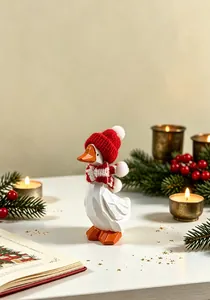 Détail d'une charmante figurine d'oie blanche en bois avec bonnet et écharpe de Noël rouges