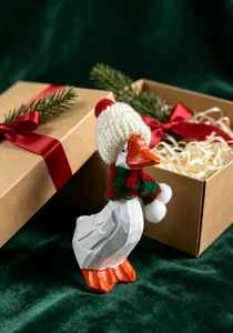 Vue détaillée d'une oie en bois sculptée avec bonnet et écharpe de Noël festifs.