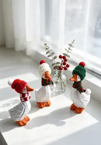 Trois figurines de canard blanc festives avec bonnets et écharpes tricotés pour Noël