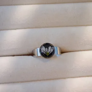 Detailansicht eines Edelstahlrings mit echter weißer Trockenblume in Harz-Cabochon