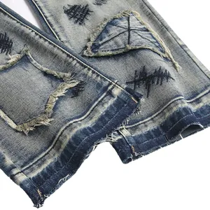 Close-up of washed blue distressed flared jeans for men with embroidery and patchwork details.