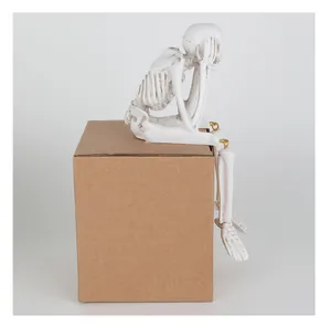 Detailweergave van een wit hars skeletbeeldje zittend op een doos voor Halloween-decoratie