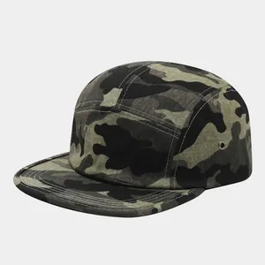 Dettaglio di un cappello 5-panel mimetico con visiera piatta e occhielli in metallo.