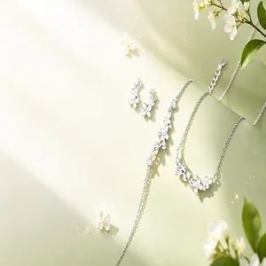Elegant silver necklace, bracelet, and earrings set with white floral charms