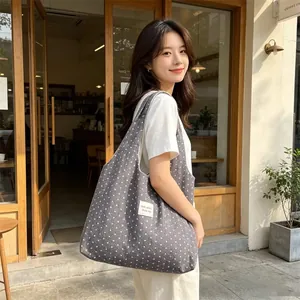 Large grey polka dot slouchy tote bag styled by a model in a cozy cafe setting