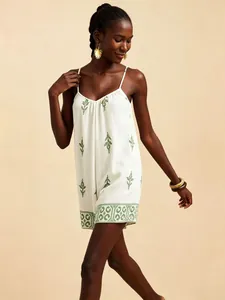 Elegante mono blanco de estilo vacacional con bordados de hojas verdes y tirantes finos.
