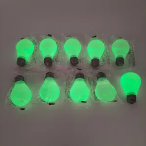 Detail of glow-in-the-dark light bulb shaped squeeze fidget toys in a dark environment.