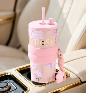 Detail of a pink floral coffee tumbler sitting in a car cup holder with a straw