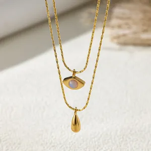 Detailed macro view of a double-layer gold necklace with Evil Eye and teardrop pendants