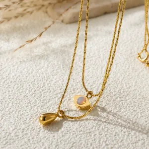 Close-up of double-layer gold necklace with angel eye and waterdrop pendant details.